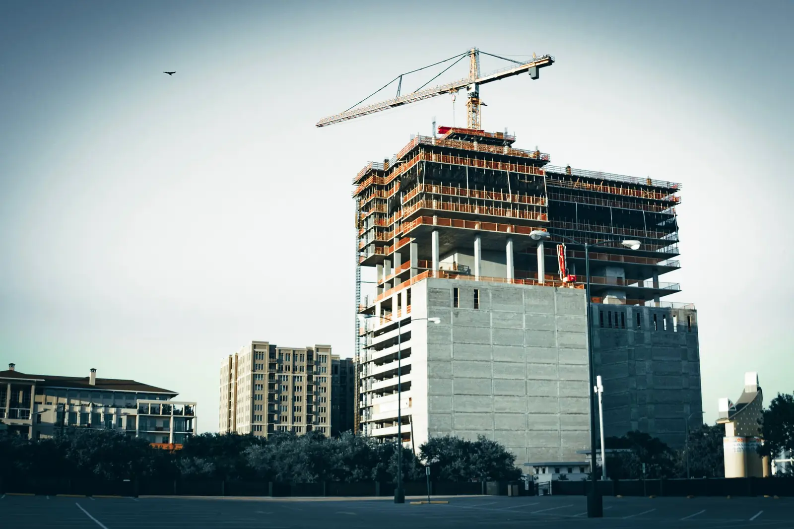 The concrete frame of a high-rise under construction, formwork and rebar exposed across several floors.